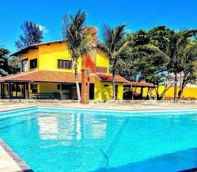Casa amarela com piscina e palmeiras em uma das unidades