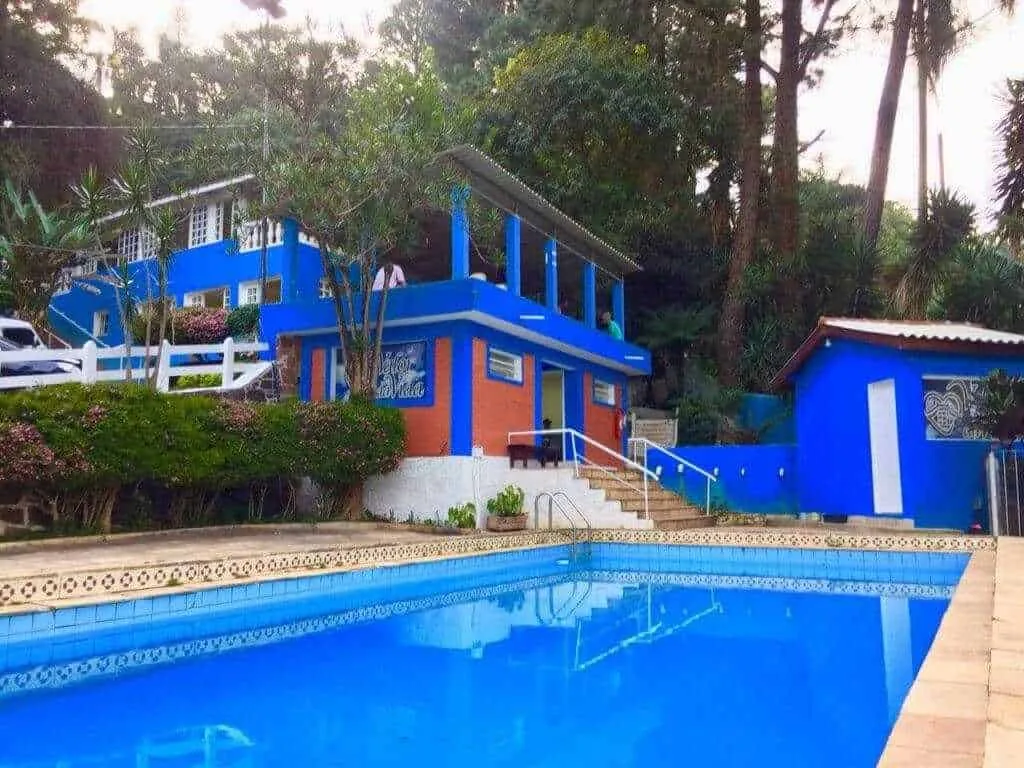 Casa azul com piscina em meio à vegetação em uma das unidades